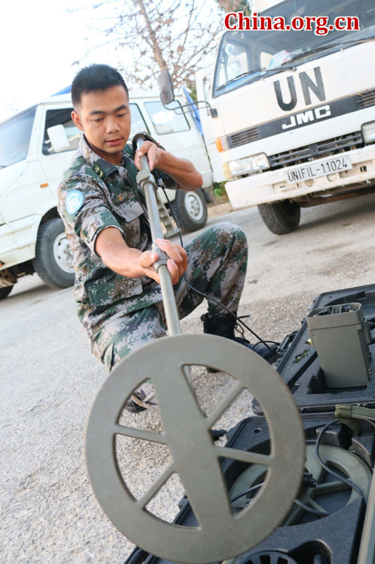 出发前，李江在检查扫雷器材。作为副组长的李江，不仅要准备好个人必带的防护装具，还要检查扫雷器材。每天他都提前半小时起床，一一打开器材箱，检查扫雷器材，查看是否有遗漏的，性能是否良好。[中国网图片库 叶洋萍 摄]